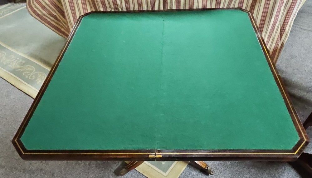 A Regency rosewood games table featuring brass inlay embellishments, a central pedestal, and splayed quadripartite legs with brass caps. View IX