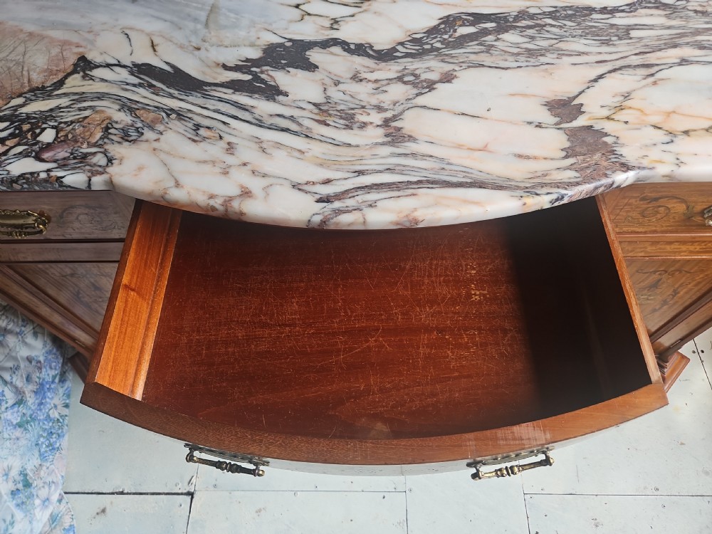 A satinwood inlaid washstand featuring a dark veined marble surface and splashback above three drawers and twin cupboard doors with inlaid urn motifs. View IV