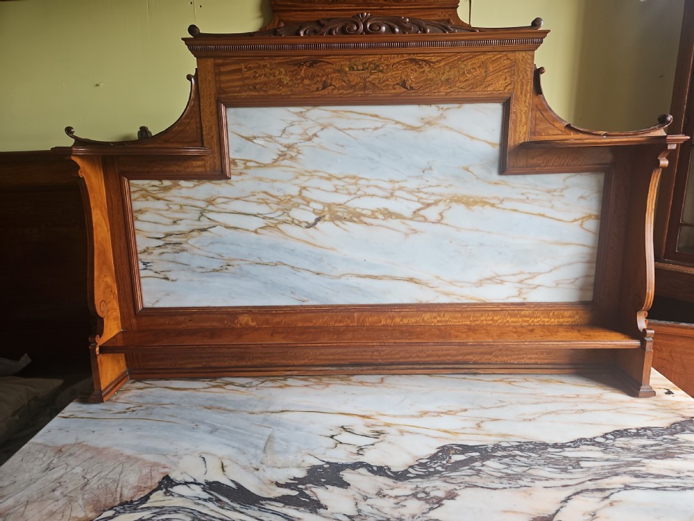 A satinwood inlaid washstand featuring a dark veined marble surface and splashback above three drawers and twin cupboard doors with inlaid urn motifs. View V