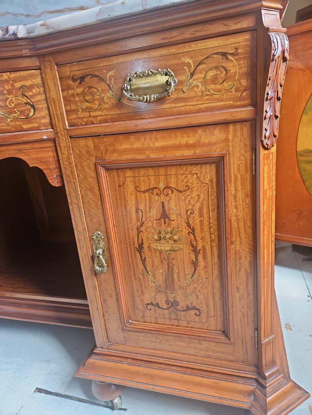A satinwood inlaid washstand featuring a dark veined marble surface and splashback above three drawers and twin cupboard doors with inlaid urn motifs. View VIII