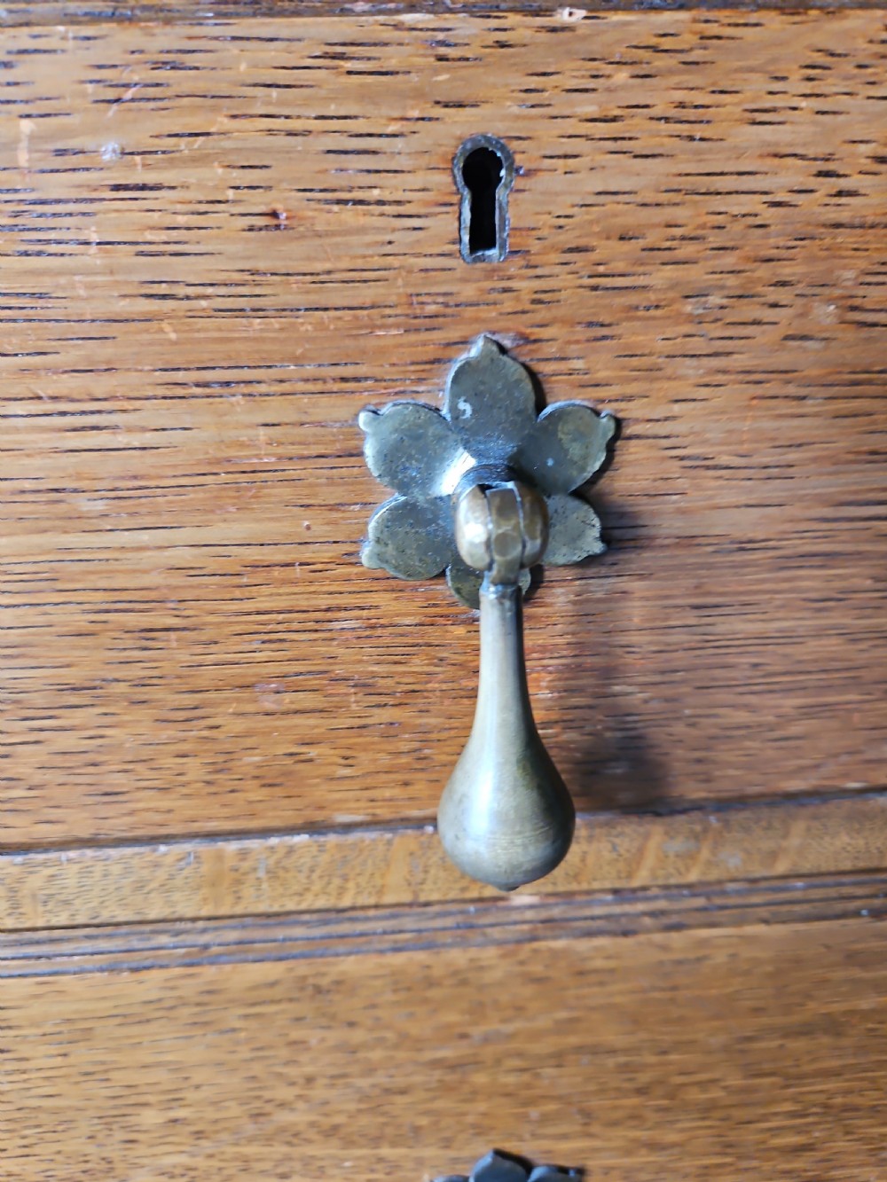 An antique oak linen press featuring an upper two-door cupboard with arched panels above four drawers with brass handles. View III