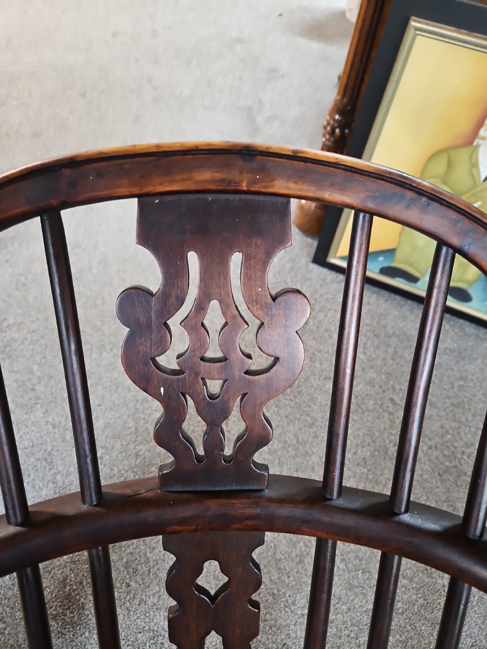 An antique dark yew wood Windsor armchair featuring a curved hoop back, a pierced central splat, turned spindles, and carved wooden arms supported by turned legs. View II