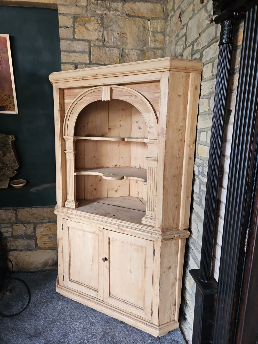 A tall Victorian pine corner cabinet with an arched open display top containing two shelves over a lower panelled double-door cupboard. View II