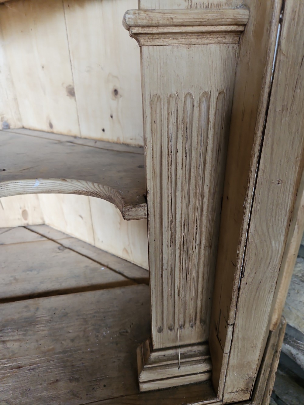 A tall Victorian pine corner cabinet with an arched open display top containing two shelves over a lower panelled double-door cupboard. View III