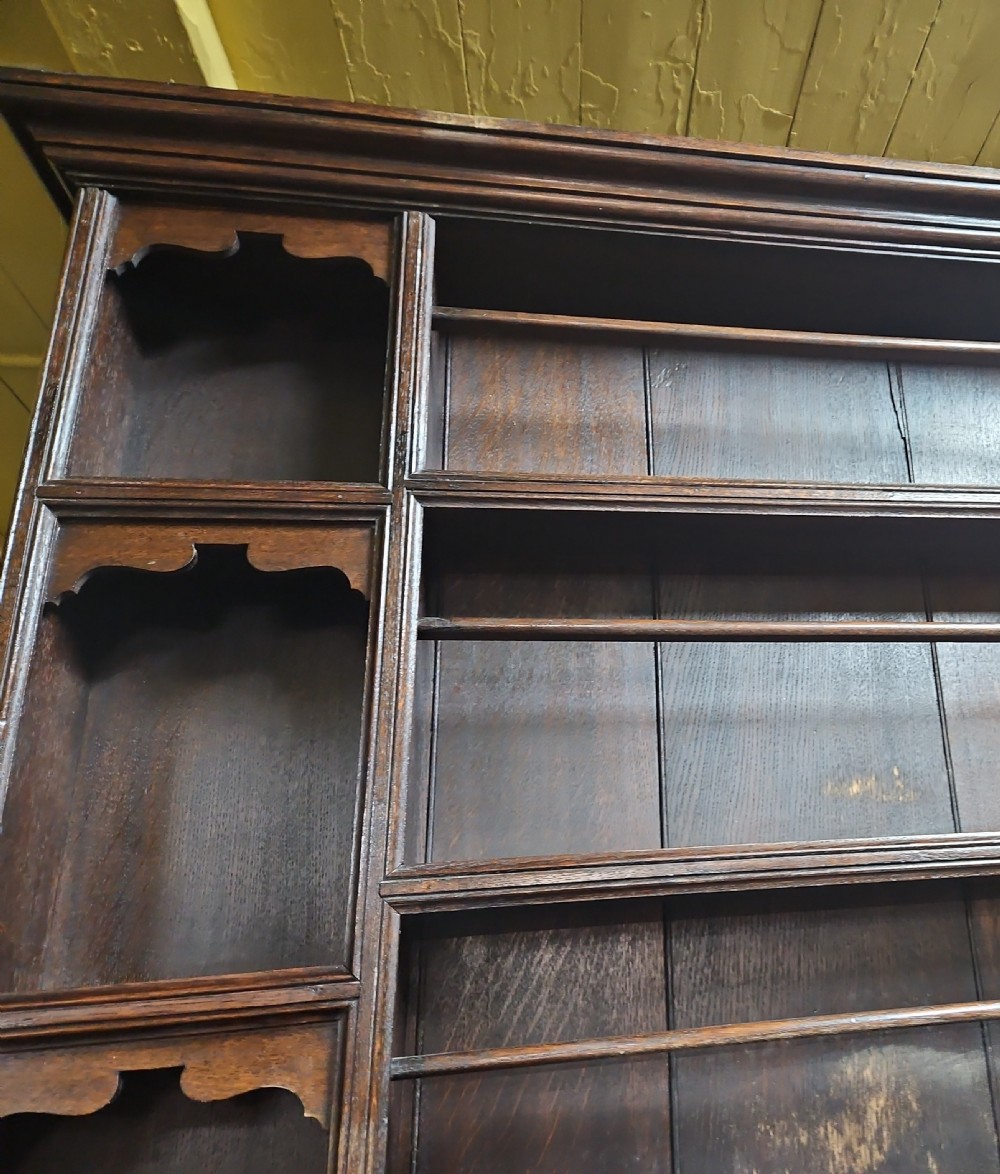 A dark oak Welsh dresser featuring a tall multi-tiered open plate rack top above three drawers with geometric mouldings and turned legs. View XI