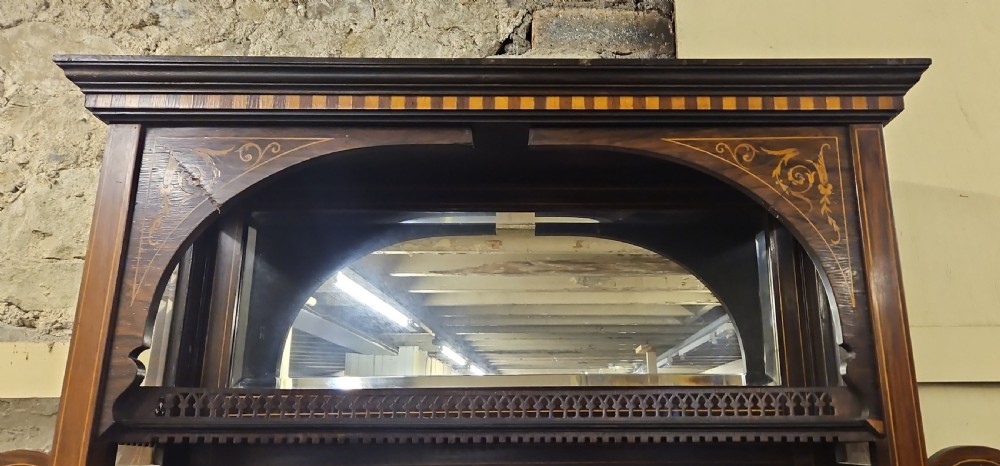 An Edwardian rosewood cabinet featuring intricate marquetry inlay, multiple mirrored panels, open tier shelving, and central glass-front doors. View VI