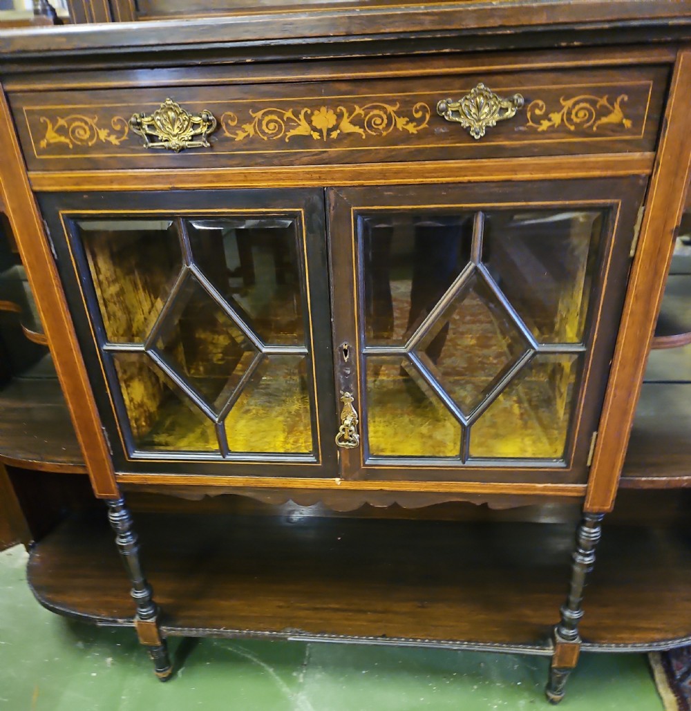 An Edwardian rosewood cabinet featuring intricate marquetry inlay, multiple mirrored panels, open tier shelving, and central glass-front doors. View VIII