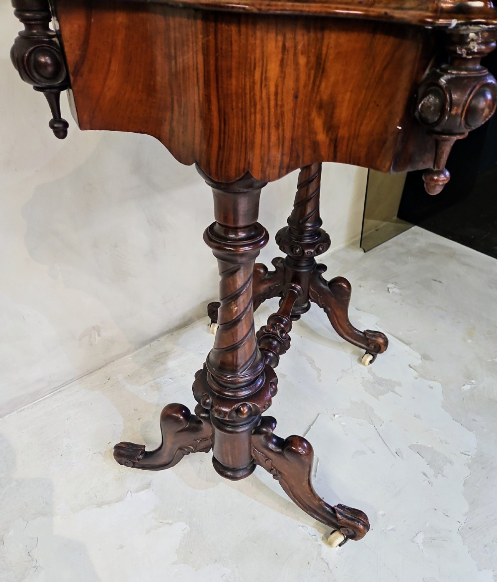 A Victorian walnut work table featuring spiral-turned twin supports, a carved central stretcher, and shaped feet resting on white porcelain castors. View IV