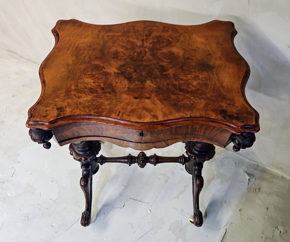 A Victorian walnut work table featuring spiral-turned twin supports, a carved central stretcher, and shaped feet resting on white porcelain castors. View V