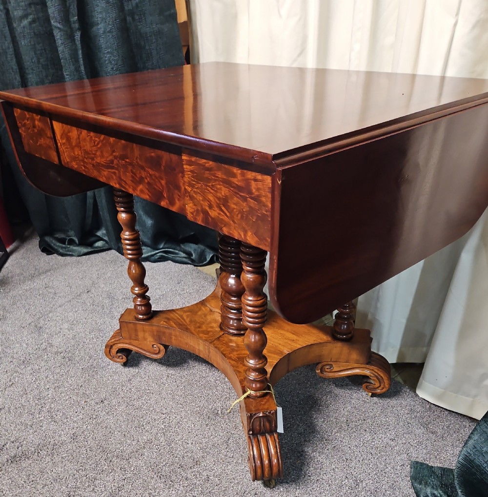 A Victorian mahogany drop-leaf sofa table with burr walnut veneered drawers, turned twin-column legs, and a shaped quadruped base on castors.