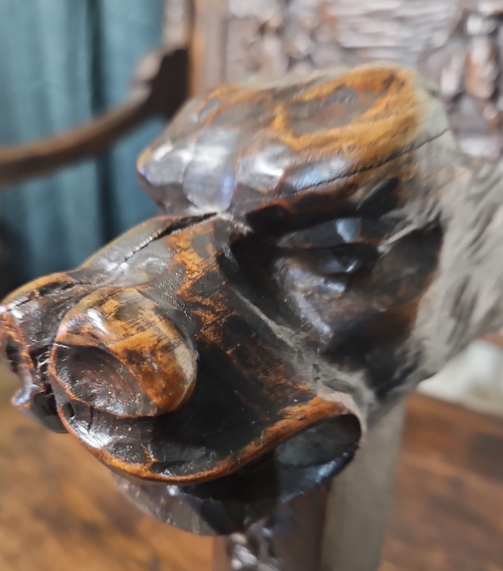 A pair of dark carved oak Breton armchairs featuring backrest panels with relief scenes of folk figures and turned spindle galleries. View V