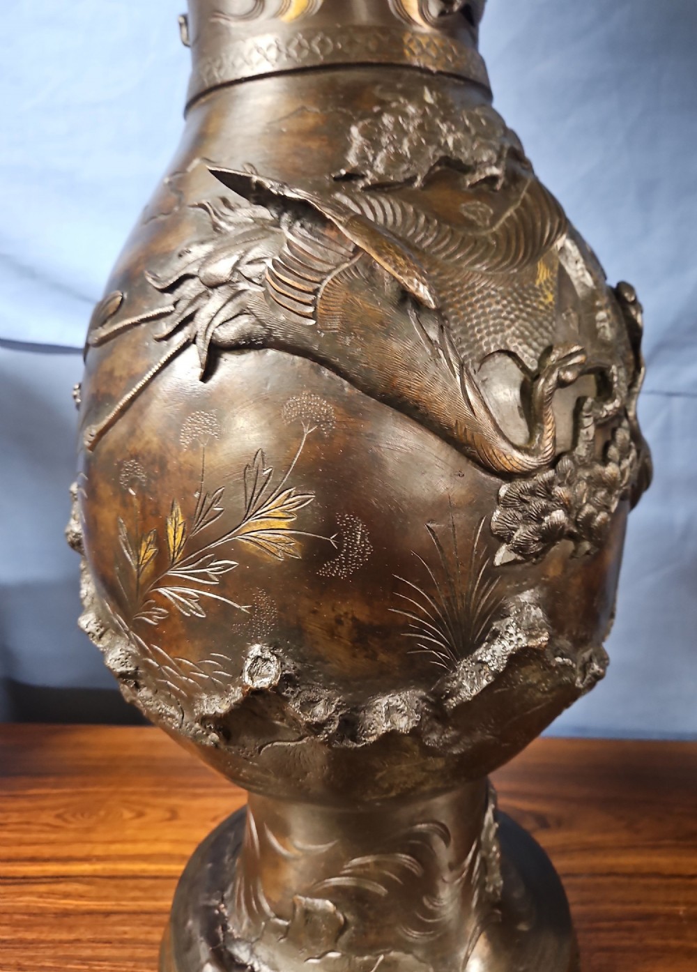 A pair of large Japanese bronze vases featuring high-relief sculpted dragons around the necks and crane motifs on bulbous bases with gilt detailing. View V
