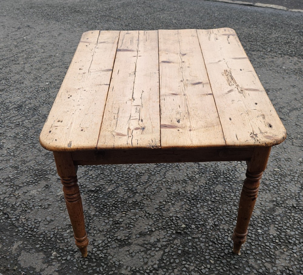 A rectangular Victorian pine table featuring a multi-plank top with visible grain patterns and four turned wooden legs.