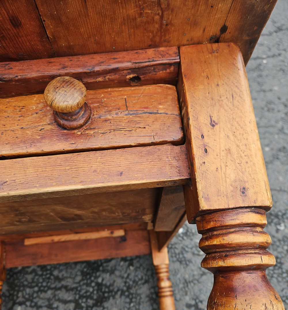 A rectangular Victorian pine table featuring a multi-plank top with visible grain patterns and four turned wooden legs. View VII