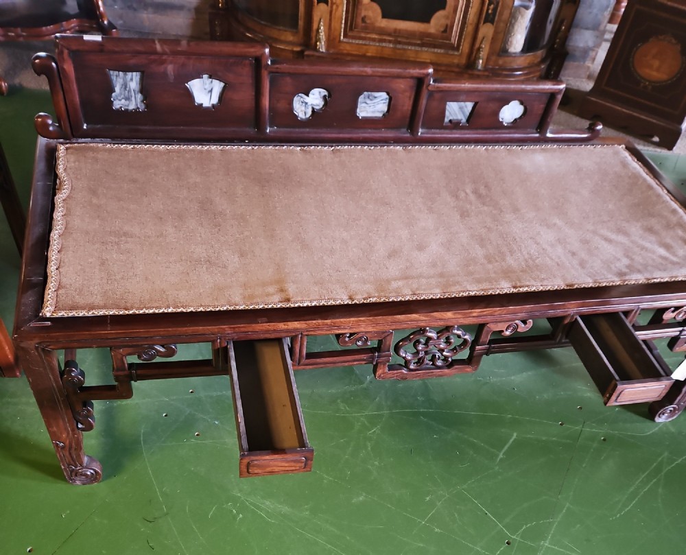A carved dark hardwood Chinese daybed featuring a stepped backrest with marble panel inserts and a tufted light brown cushioned seat. View VII