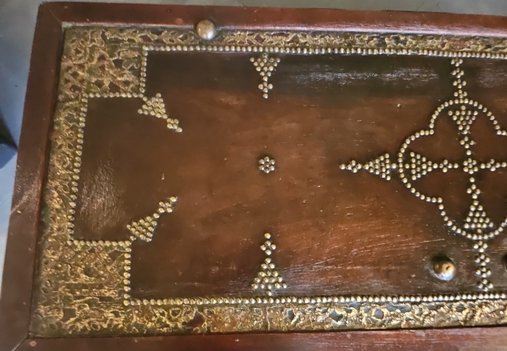 A mid-Victorian wooden Zanzibar chest decorated with intricate brass studs, geometric brass sheeting, and three base drawers. View XII