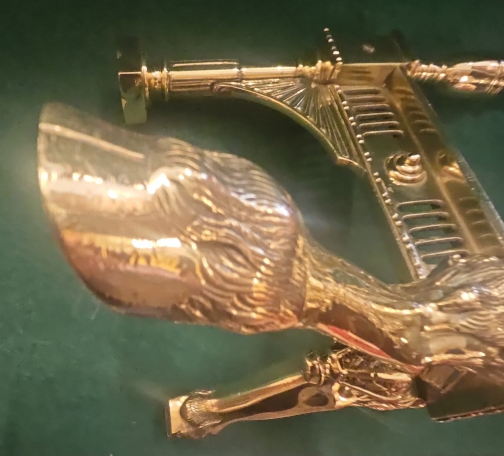A pair of polished brass Regency fire dogs featuring classical urn finials and splayed support feet. View IV