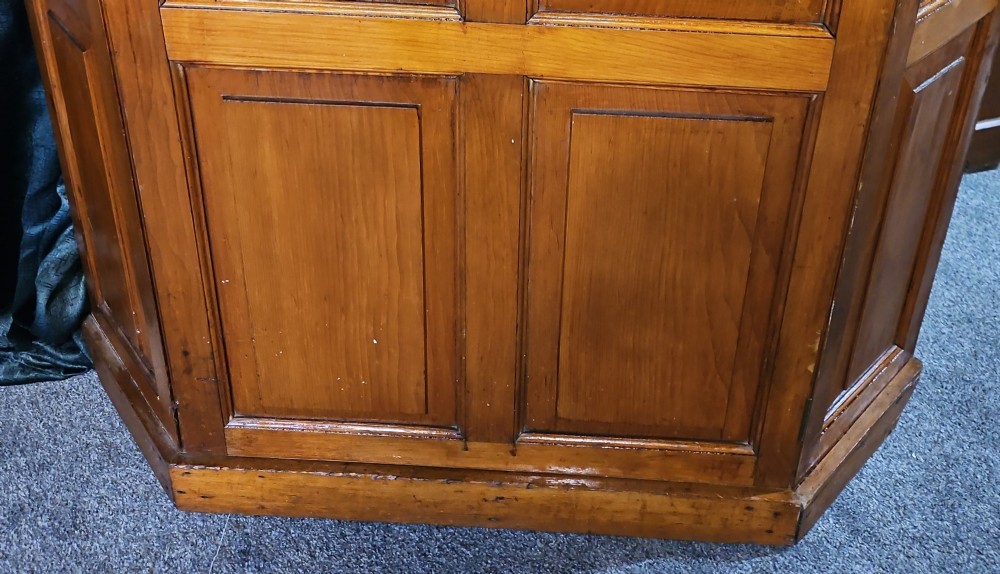 A tall Victorian pine corner wardrobe with fielded panel doors, a brass escutcheon, and a moulded cornice. View II