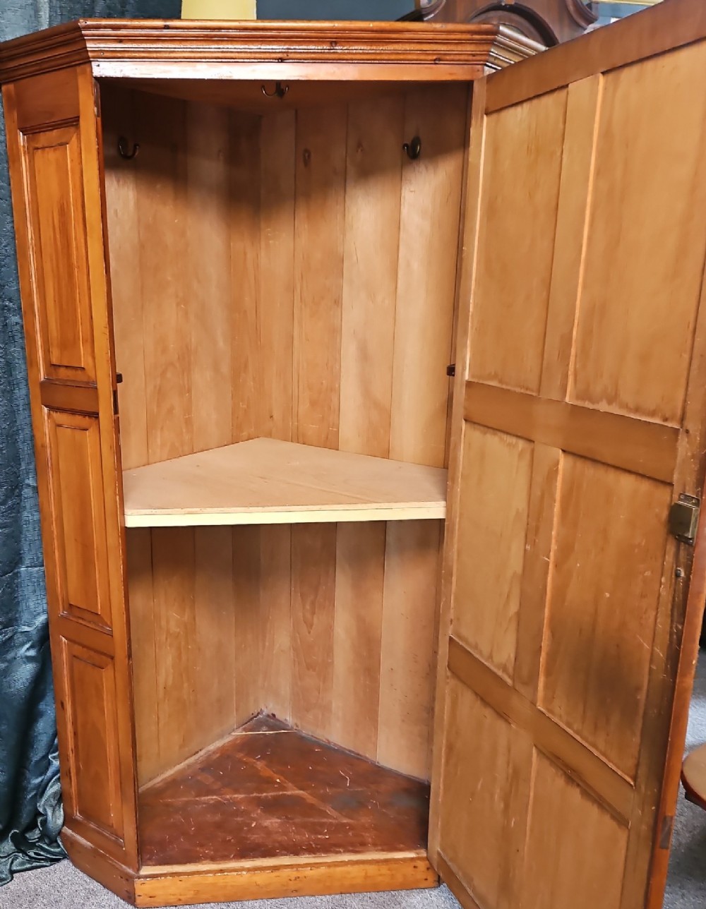 A tall Victorian pine corner wardrobe with fielded panel doors, a brass escutcheon, and a moulded cornice. View VI