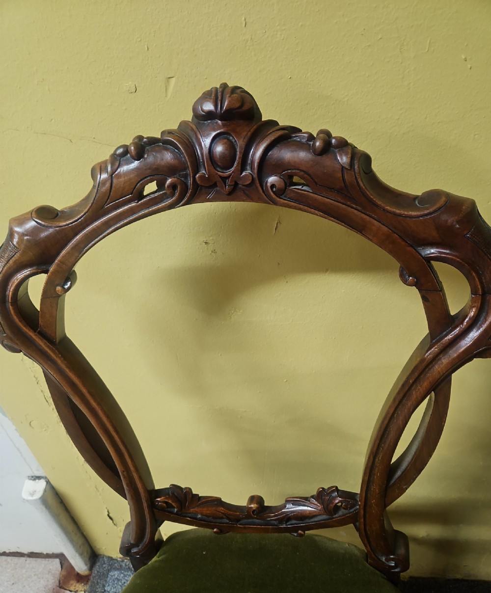 A pair of Victorian carved walnut balloon-back side chairs featuring olive green velvet upholstered seats and front cabriole legs. View II