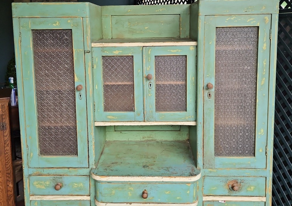 A distressed green painted pine kitchen cabinet featuring upper glazed doors, drawers, and lower panelled wooden doors. View II