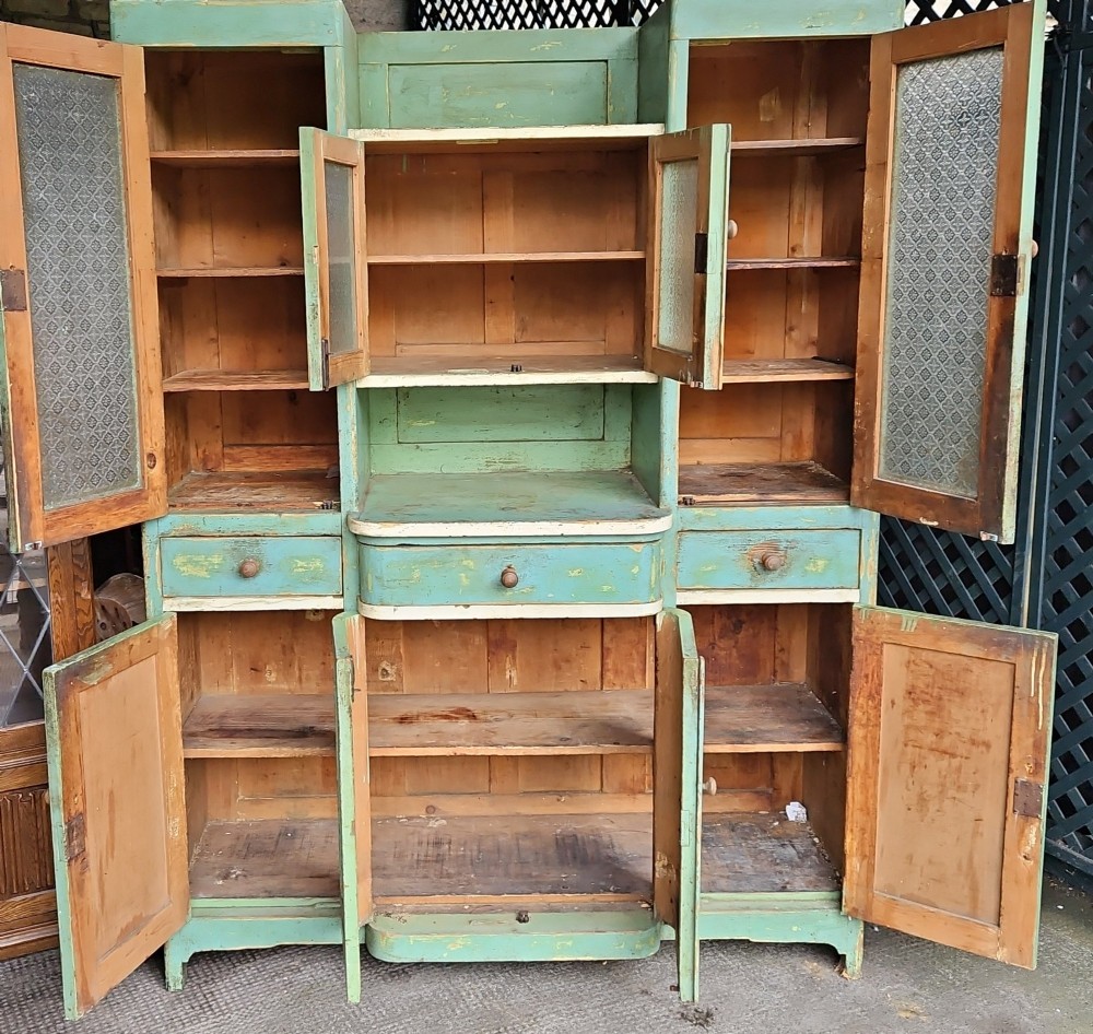 A distressed green painted pine kitchen cabinet featuring upper glazed doors, drawers, and lower panelled wooden doors. View VIII