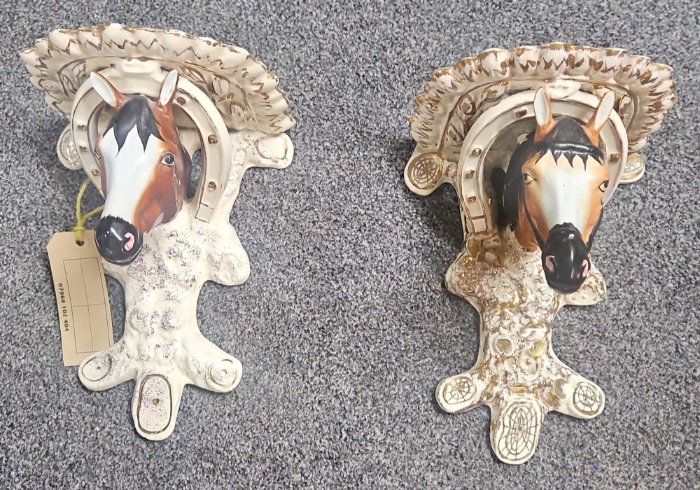 A pair of Victorian Staffordshire earthenware wall brackets featuring moulded horse heads framed by horseshoes with gilded decorative borders.