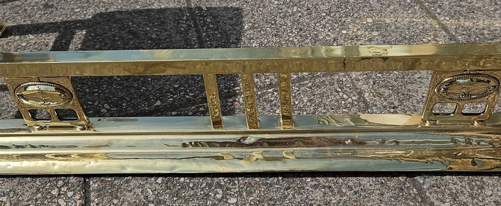 A Victorian brass club fender featuring a polished metal frame with upright supports and two red leather buttoned seats. View IX