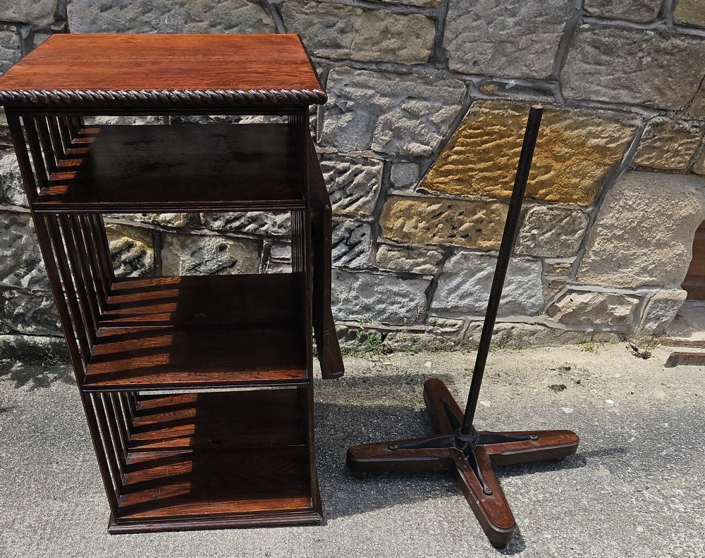 An Edwardian oak revolving bookcase shown disassembled alongside its central cast iron post and quadform wooden base.