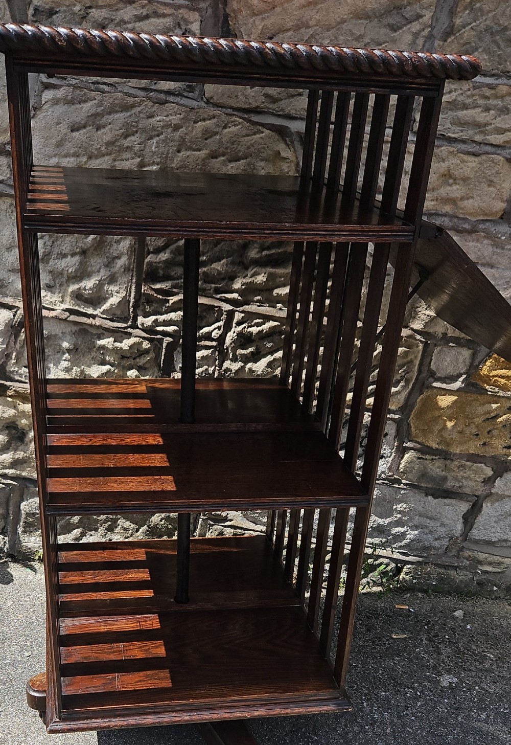 An Edwardian oak revolving bookcase shown disassembled alongside its central cast iron post and quadform wooden base. View II