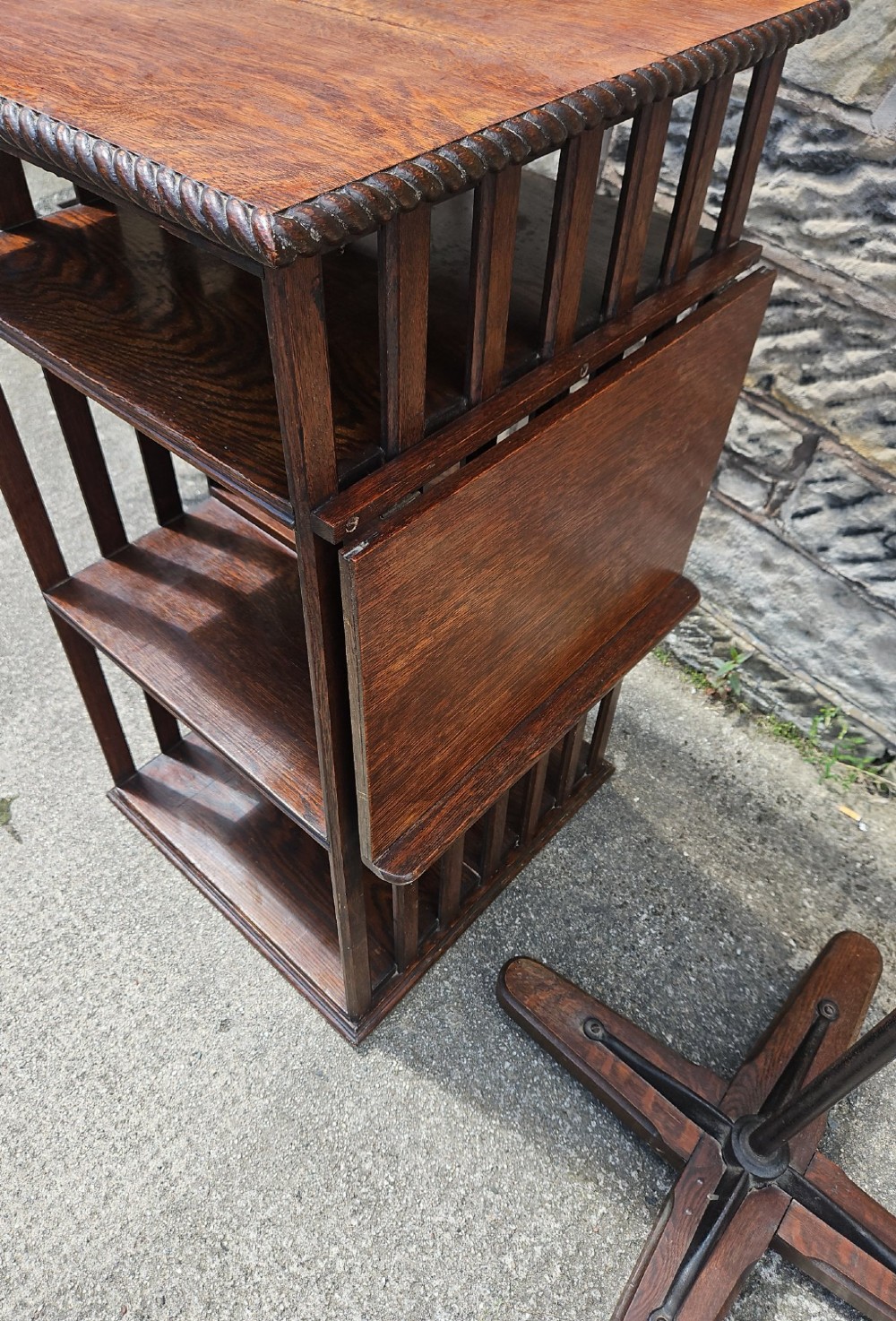 An Edwardian oak revolving bookcase shown disassembled alongside its central cast iron post and quadform wooden base. View VII