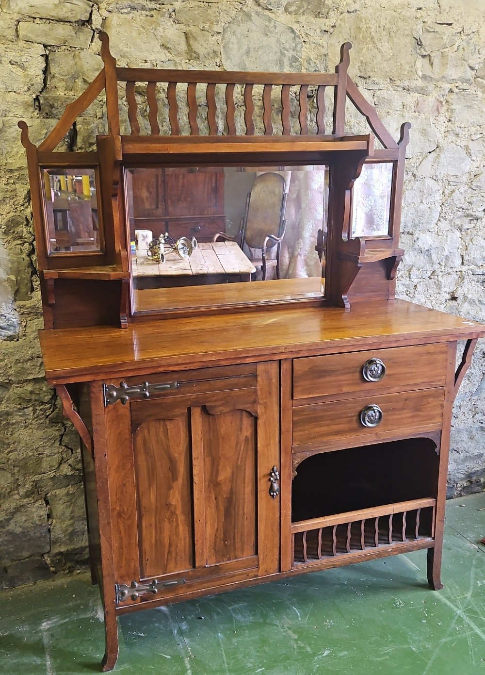 An Arts and Crafts solid wood sideboard featuring decorative iron strap hinges, a central mirror superstructure with upper spindle gallery, and lower storage drawers and cupboard. View III
