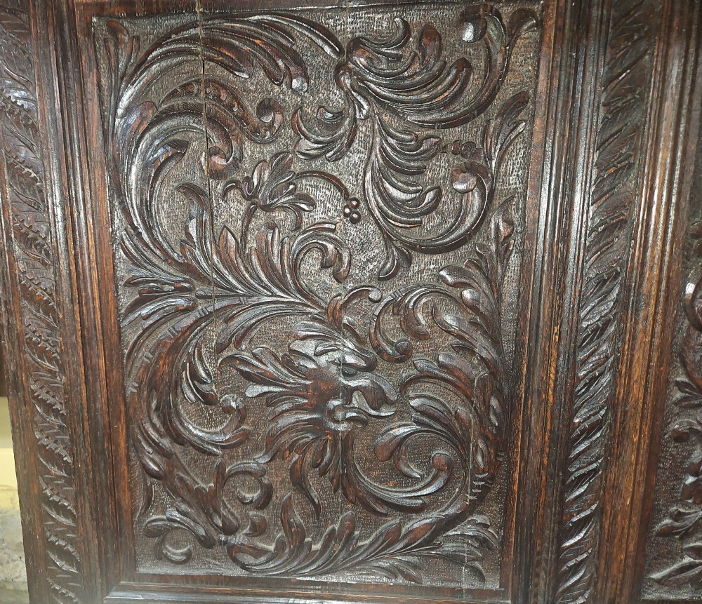 A heavily carved dark oak Jacobean style dresser featuring an open tiered upper rack supported by barley twist columns over a three-door base cupboard with carved relief panels. View IV