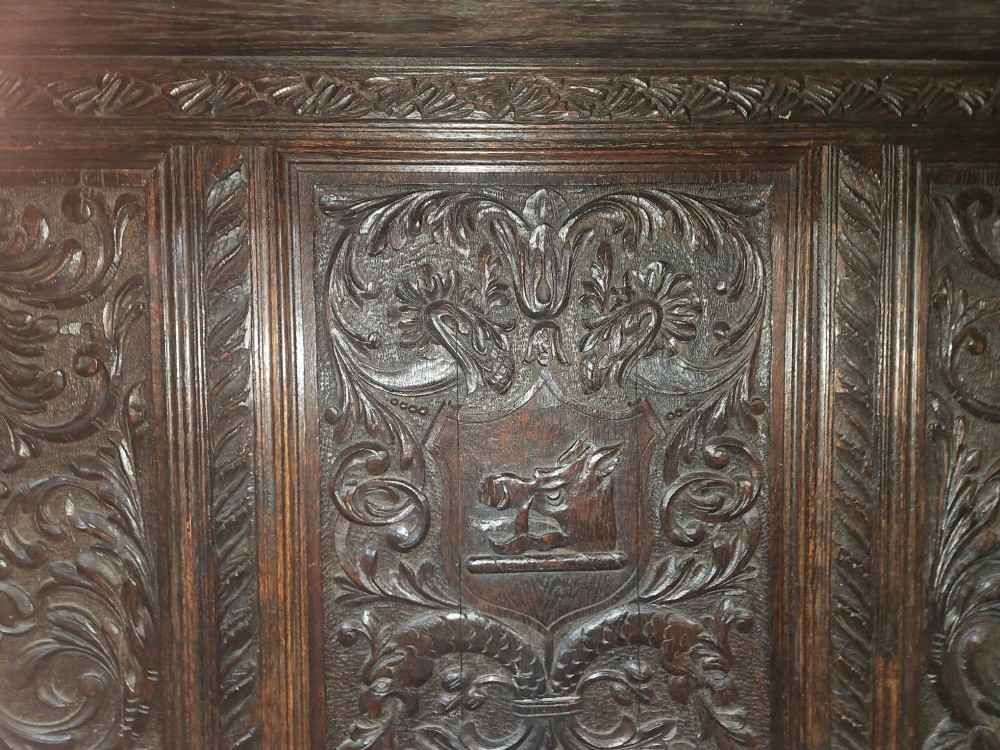 A heavily carved dark oak Jacobean style dresser featuring an open tiered upper rack supported by barley twist columns over a three-door base cupboard with carved relief panels. View VI