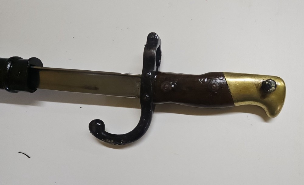 A late 19th-century French military bayonet hilt with a brass pommel, walnut handle scales, a curved steel quillon, and a metal scabbard. View III