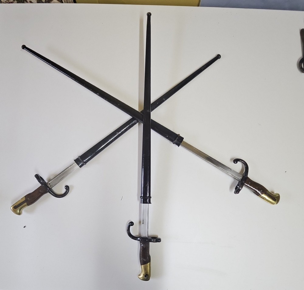A late 19th-century French military bayonet hilt with a brass pommel, walnut handle scales, a curved steel quillon, and a metal scabbard. View IV