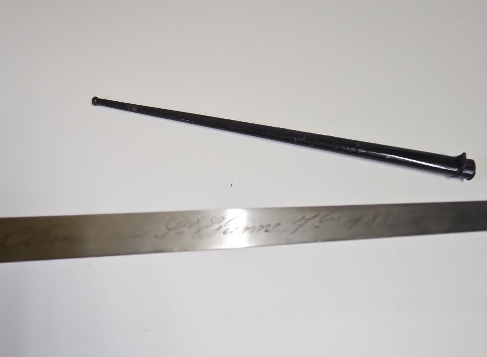 A late 19th-century French military bayonet hilt with a brass pommel, walnut handle scales, a curved steel quillon, and a metal scabbard. View V