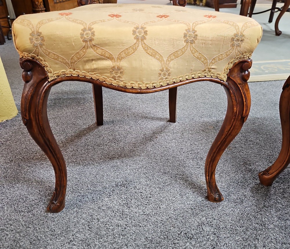 A set of four Victorian carved walnut chairs featuring intricate openwork scroll backrests, patterned cream upholstery, and cabriole legs. View VIII