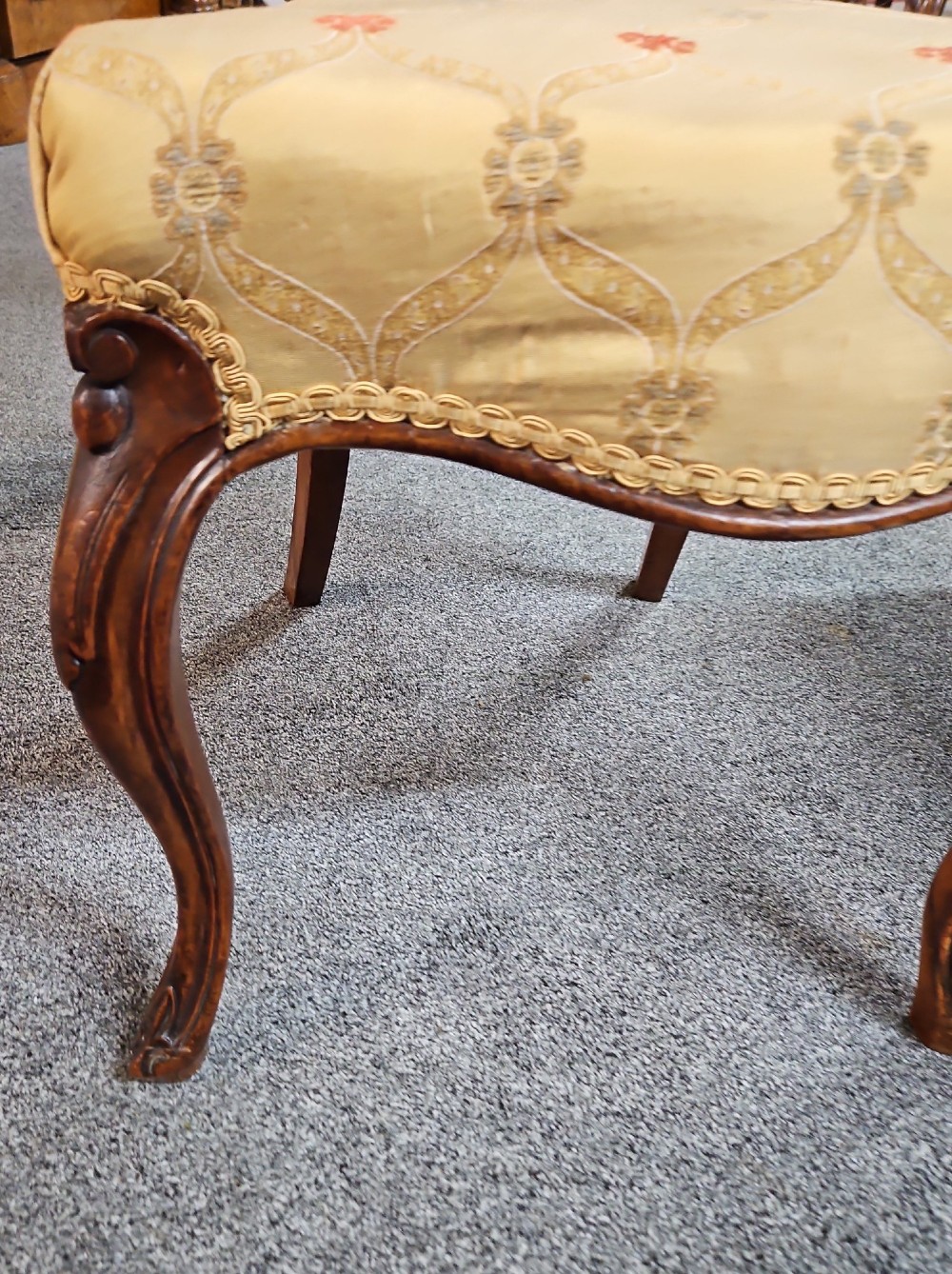 A set of four Victorian carved walnut chairs featuring intricate openwork scroll backrests, patterned cream upholstery, and cabriole legs. View X