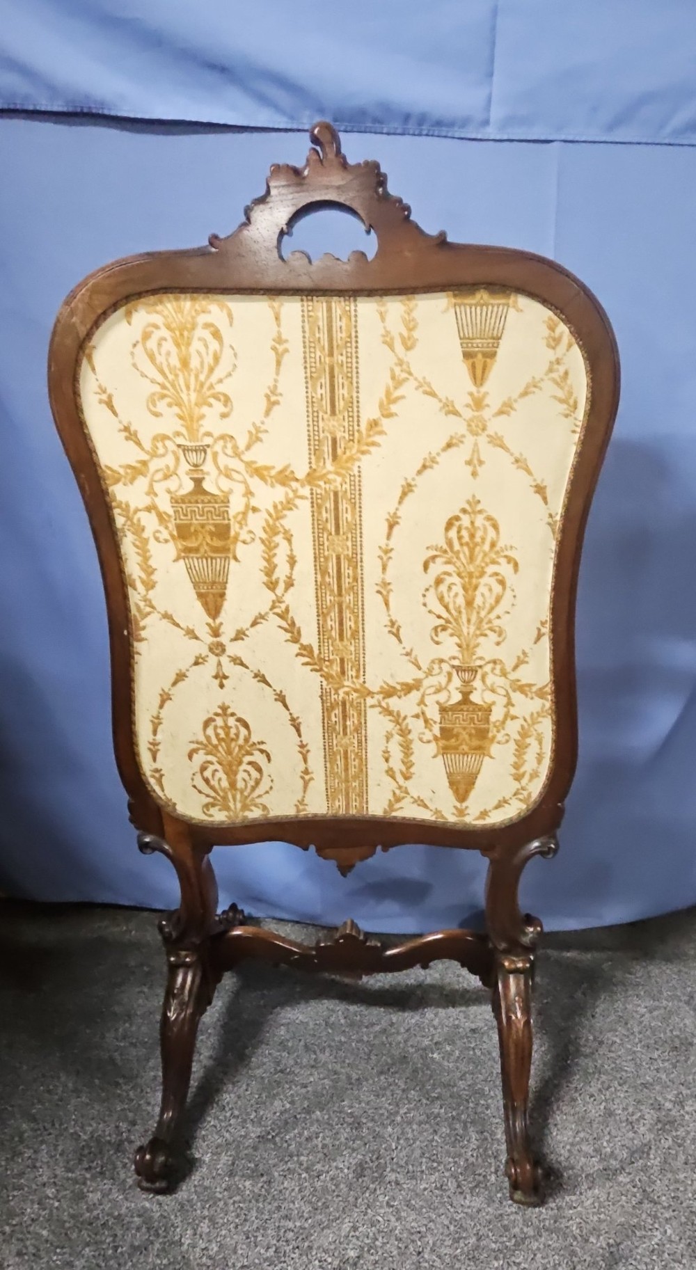 A Victorian carved walnut fire screen featuring an ornate cresting frame supported by cabriole legs, encasing a floral needlepoint textile panel. View III
