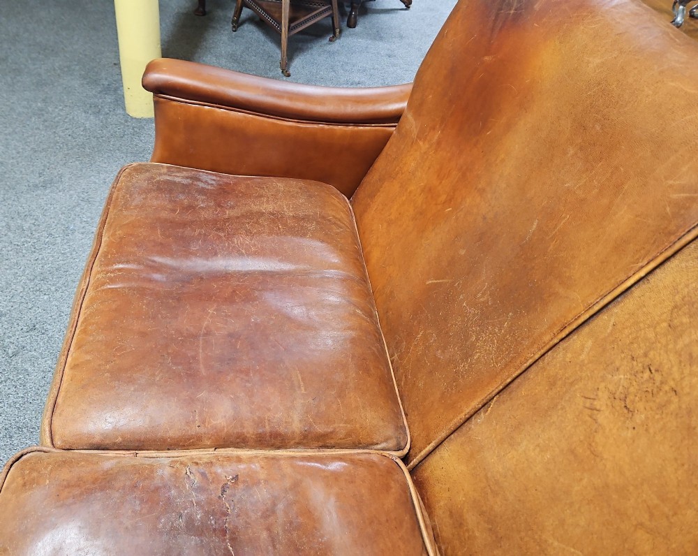 An Edwardian warm brown leather sofa featuring aged surface patina, loose seat cushions, and short tapered wooden legs. View III