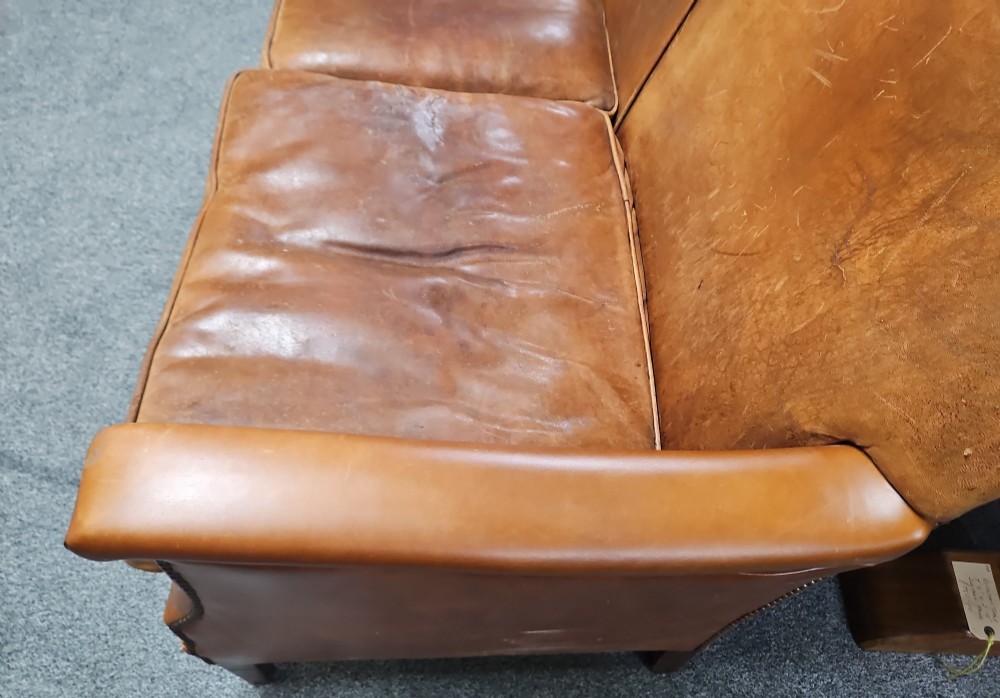 An Edwardian warm brown leather sofa featuring aged surface patina, loose seat cushions, and short tapered wooden legs. View IV