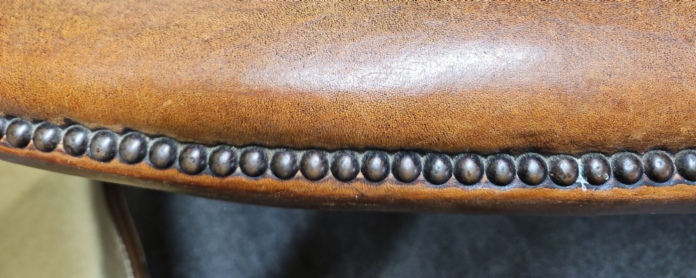 An Edwardian warm brown leather sofa featuring aged surface patina, loose seat cushions, and short tapered wooden legs. View VII