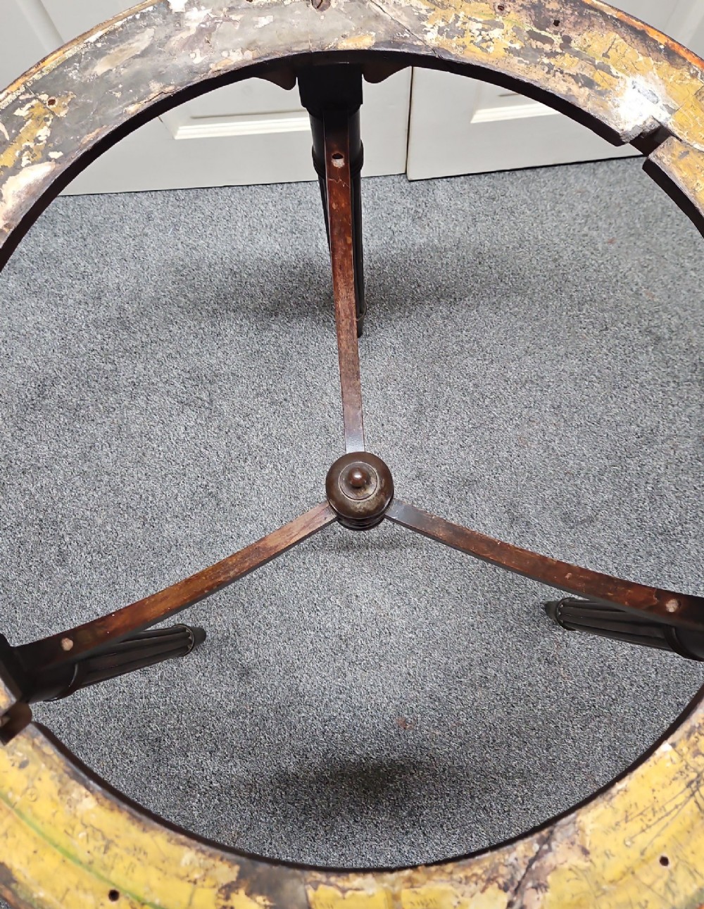 A dark mahogany circular globe stand featuring three fluted turned legs and a worn printed paper horizon ring. View V