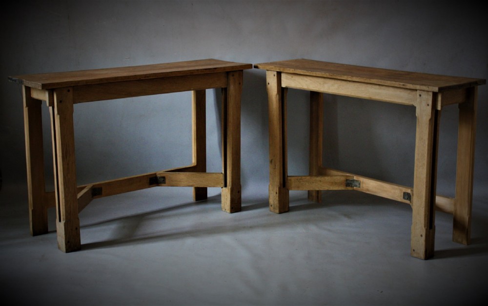 A pair of matching natural oak console tables in the Arts and Crafts style featuring straight rectangular tops, square legs, and Y-shaped lower stretchers.