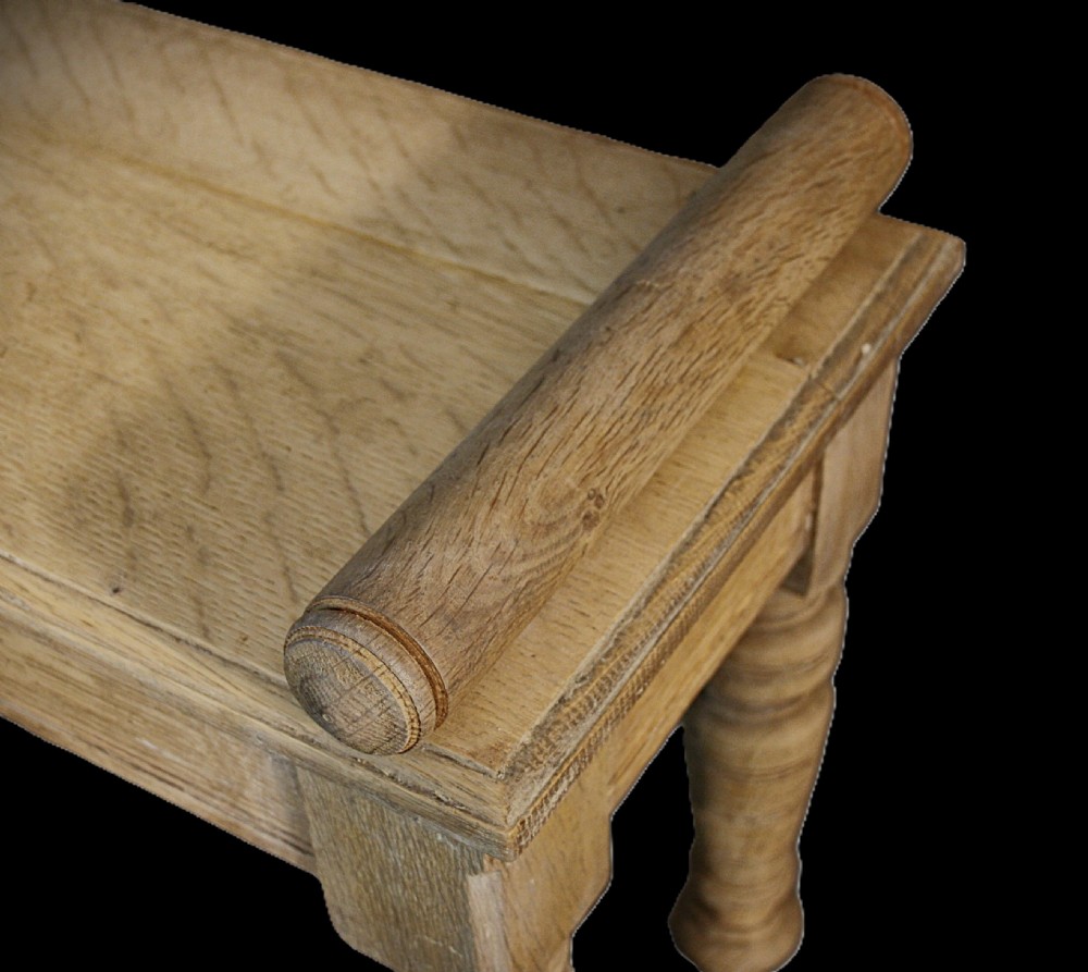 A long rectangular pale bleached oak window bench featuring turned wooden legs and cylindrical side bolsters. View II