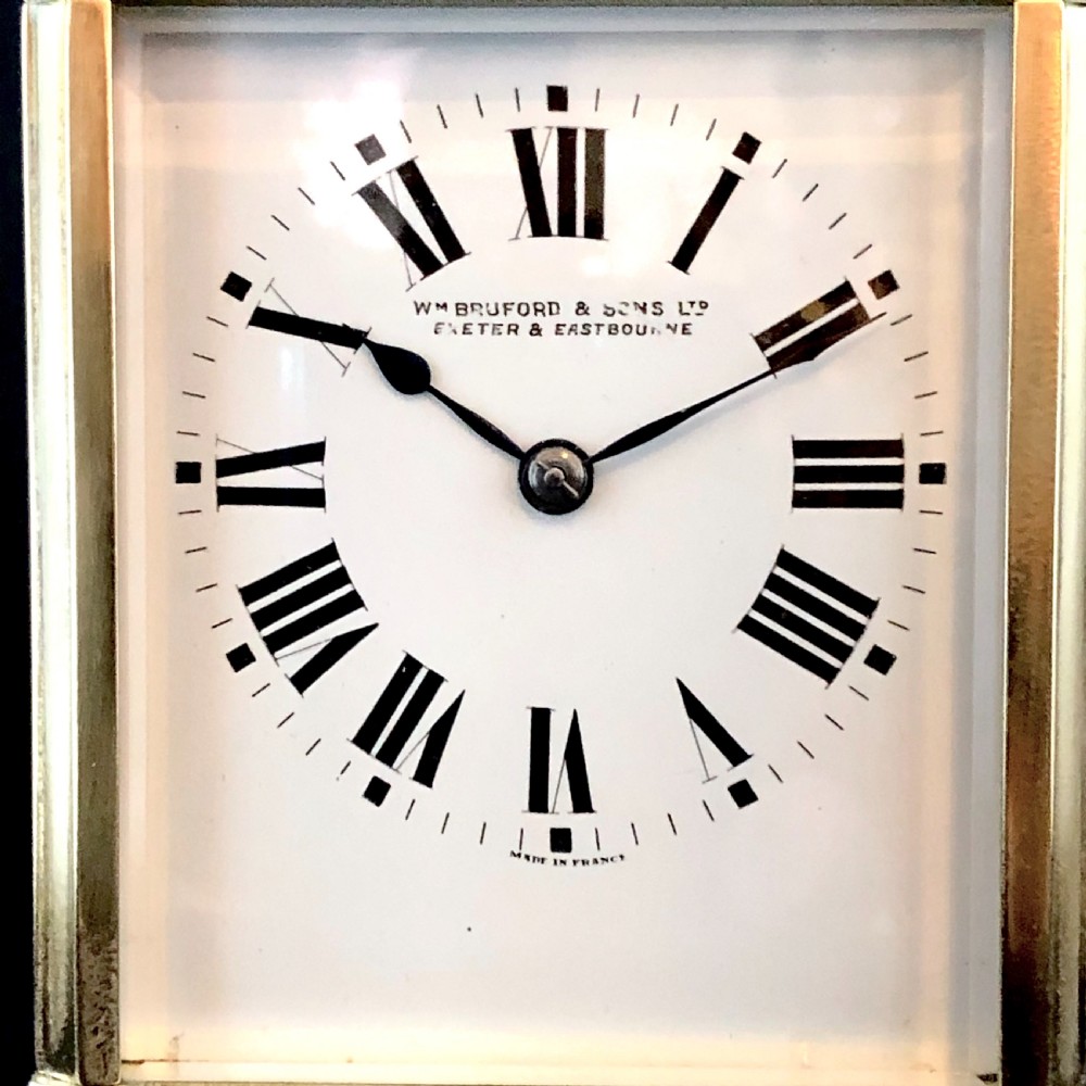 A late 19th-century French gilt brass carriage clock with bevelled glass panels, a top carrying handle, and a white enamel dial displaying Roman numerals. View VI