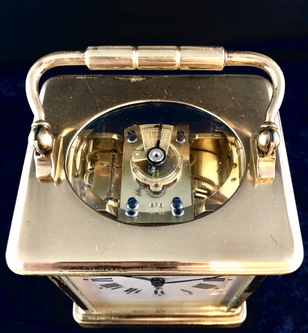 A late 19th-century French gilt brass carriage clock with bevelled glass panels, a top carrying handle, and a white enamel dial displaying Roman numerals. View VII