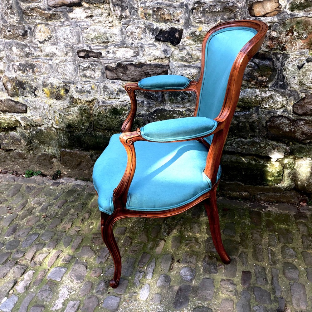 A Louis XV style open armchair crafted with a carved wooden frame, cabriole legs, and vibrant blue silk upholstery on the seat, backrest, and padded armrests. View IV