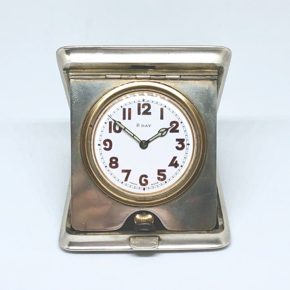 An early 20th-century silver folding travel clock by Mappin and Webb, featuring a square metallic case with a circular white dial and dark Arabic numerals.